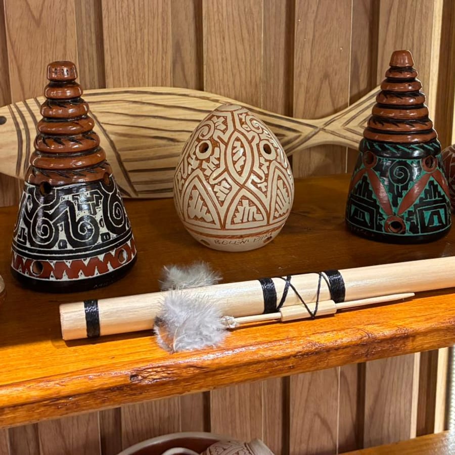 Os mesmos cones de cerâmica na prateleira do salão, entre pequenos vasos e um peixe de madeira