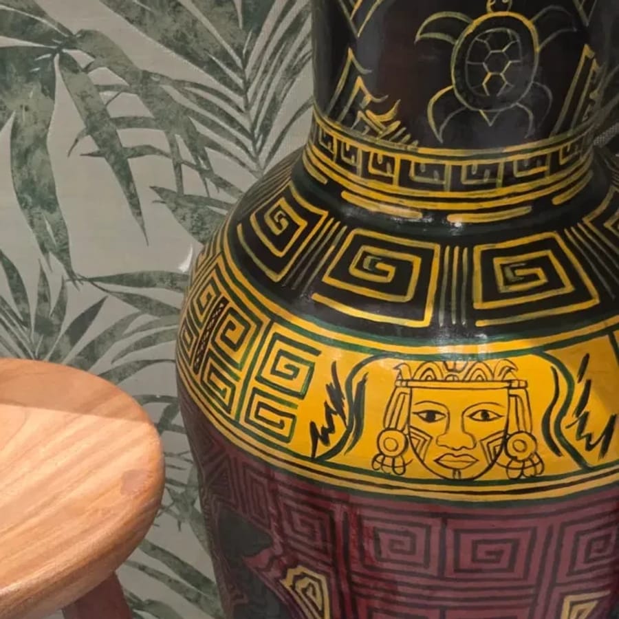 Vaso grande de cerâmica com gregas amarelas sobre fundo preto, um rosto coroado no ombro e uma tartaruga no gargalo